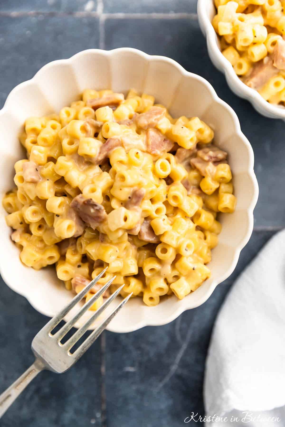 A bowl of homemade macaroni and cheese with a fork sitting next to it.