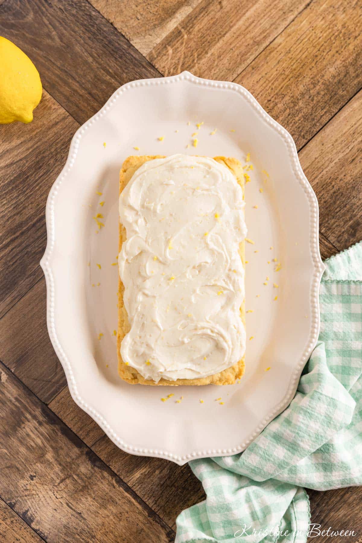 Lemon sugar cookie bars sitting on a white scalloped platter with a teal napkin next to them.