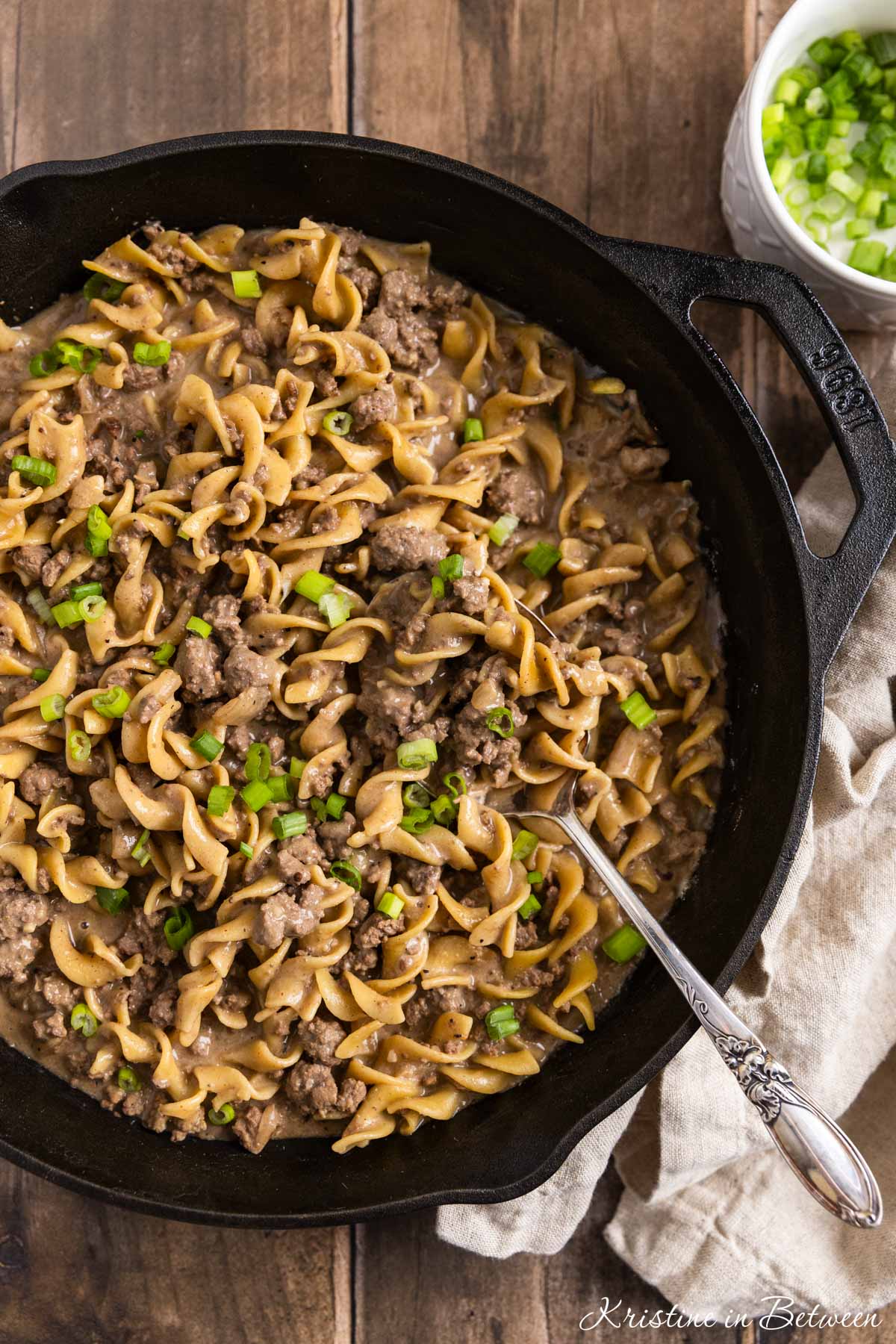 Ground beef stroganoff in a cast iron skillet with an antique spoon.
