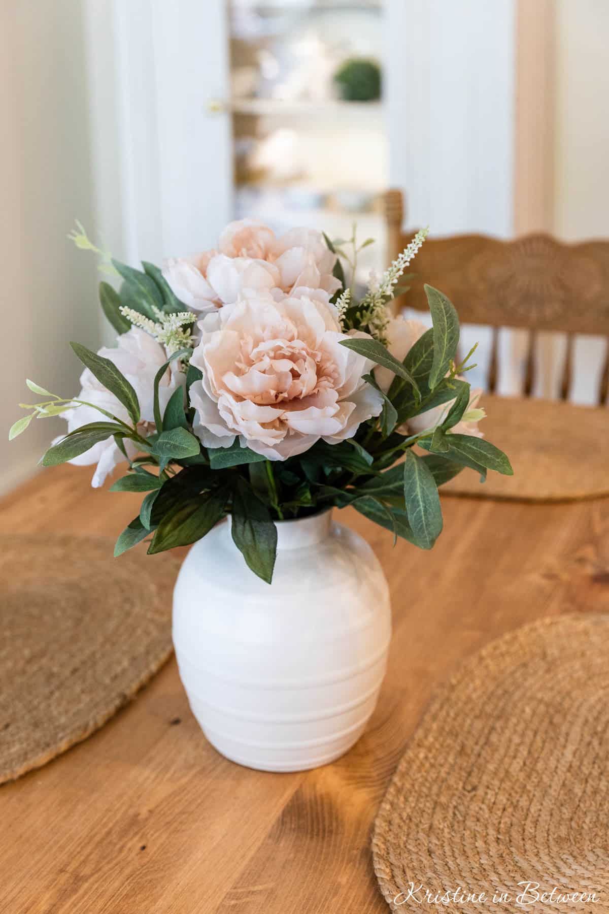 Artificial flowers in a vase on a wooden table.