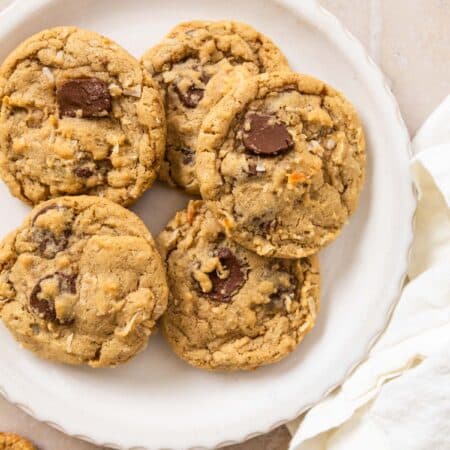 A plate of chocolate chip coconut cookies with a white napkin laying next to them.