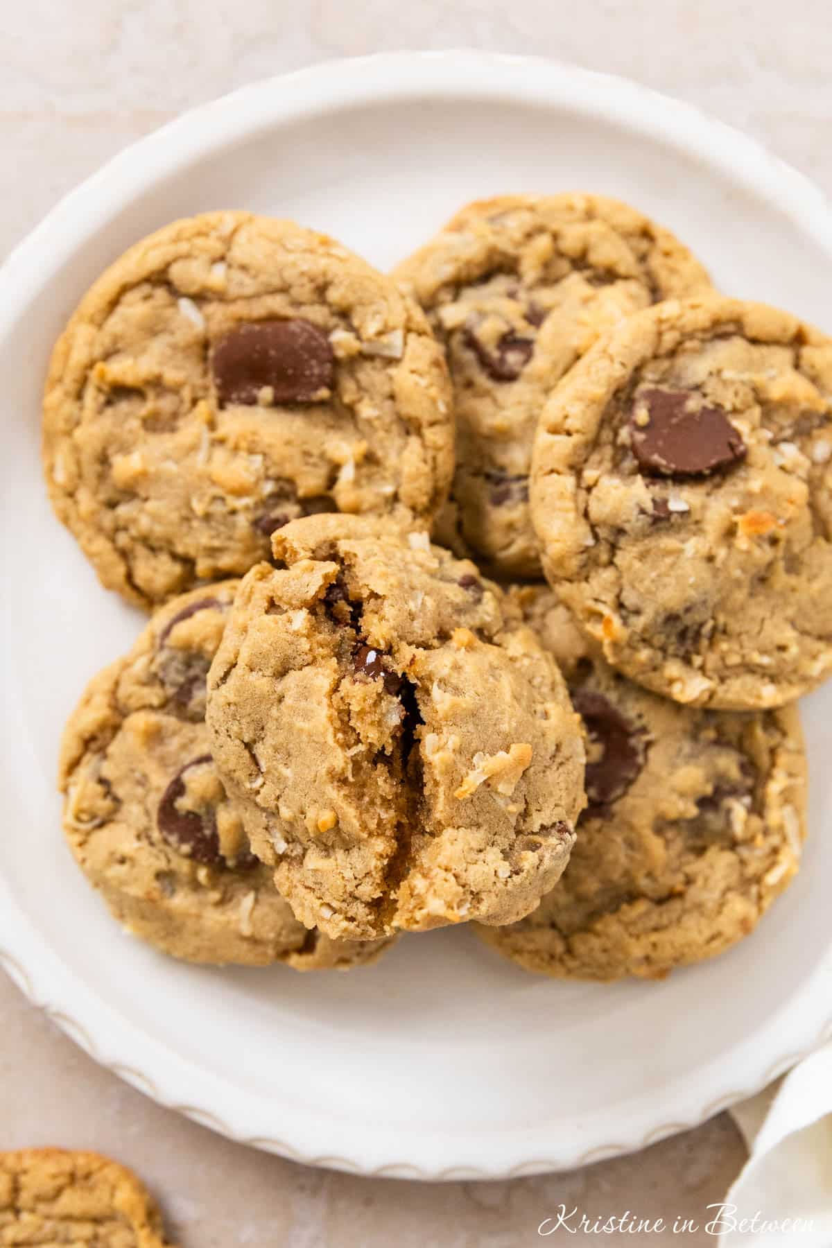 A plate of chocolate chip coconut cookies with a white napkin laying next to them.