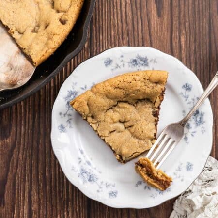 A bite of a skillet cookie on a fork with the rest of the slice on a plate.