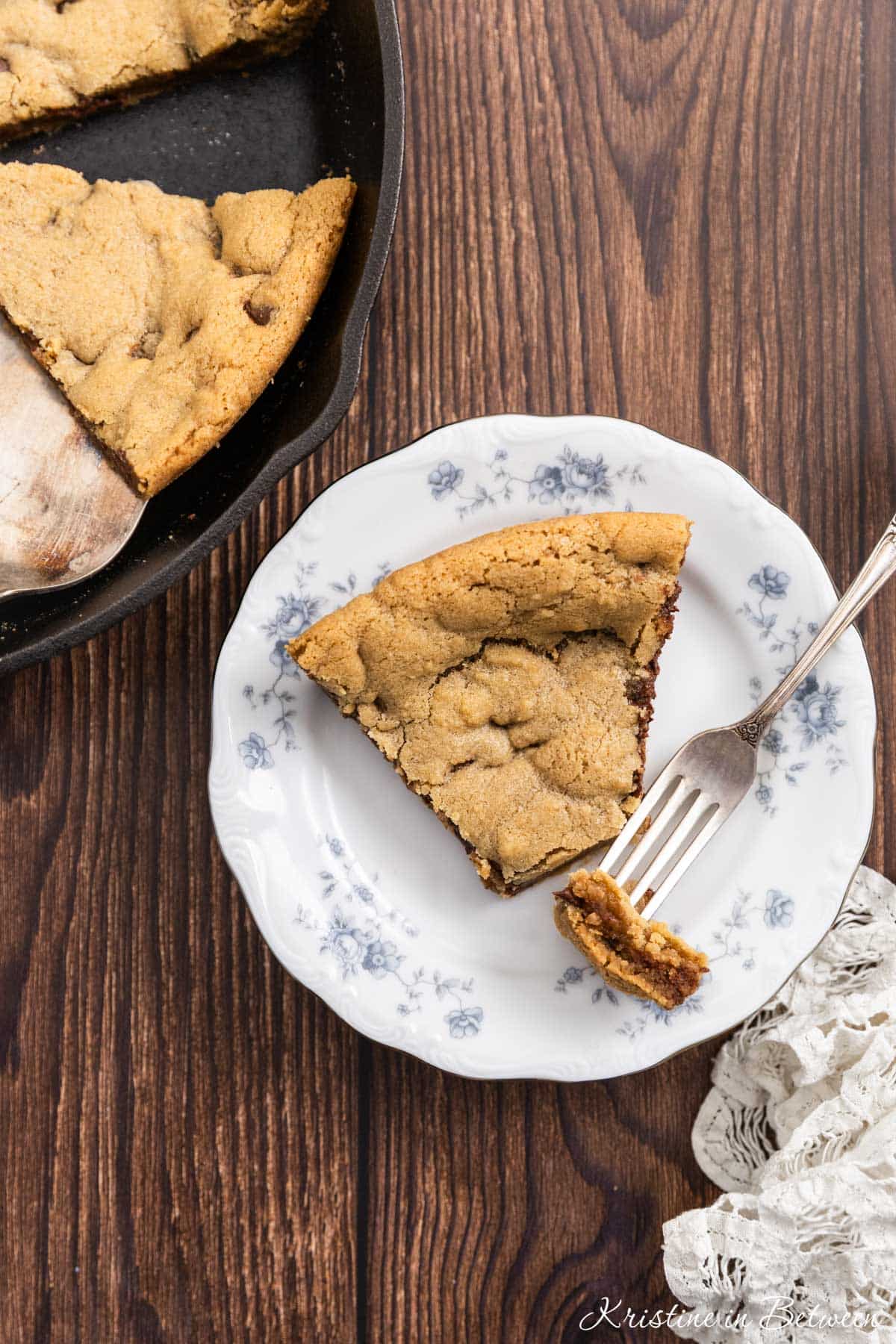 A bite of a skillet cookie on a fork with the rest of the slice on a plate.